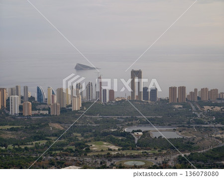 Serene waterfront with distant islet, Urban seafront featuring clustered towers and calm waters 136078080