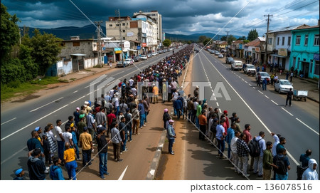 A long line of people standing on the side of a road 136078516