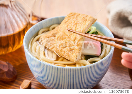 Kitsune udon noodles served with large fried tofu and kamaboko fish cake Kitsune udon noodles served with large fried tofu and kamaboko fish cake 136078678