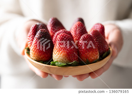 Fresh organic strawberry with green leaf on wooden plate holding by hand 136079165