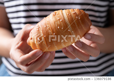 Salt bread (Shio pan) with sea salt flakes holding by woman hand and eating, Japanese bakery style Salt bread (Shio pan) with sea salt flakes holding by woman hand and eating, Japanese bakery style 136079186