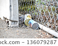A can littered on a roadside fence 136079287