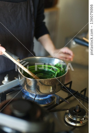 Boiling spinach in a pot 136079866