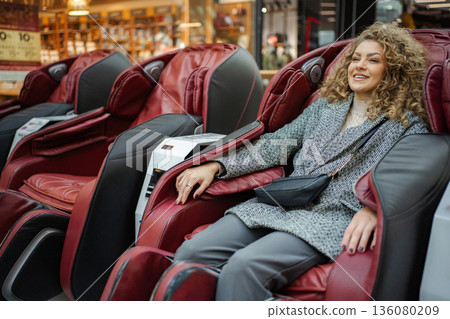 Happy woman experiencing a relaxing massage chair 136080209
