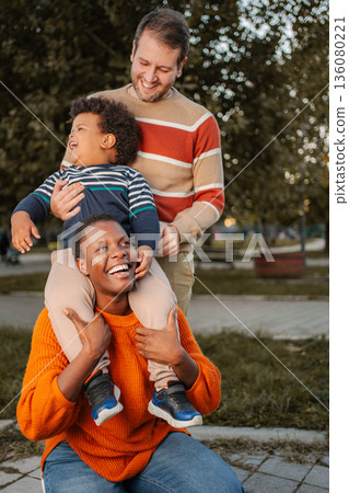 Happy multiracial family playing in park outdoors 136080221