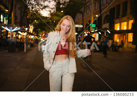 Young woman smiling while walking on Vienna city street at night Young woman smiling while walking on Vienna city street at night 136080233
