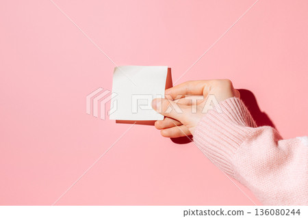 Hand holding blank sticky note pad on pink background Hand holding blank sticky note pad on pink background 136080244