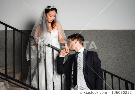 Groom kissing bride's hand on wedding day stairs Groom kissing bride's hand on wedding day stairs 136080252