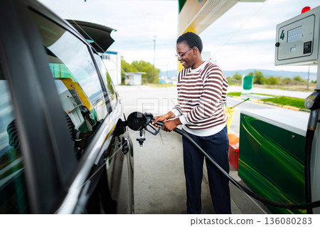 African American woman fueling car at gas station 136080283