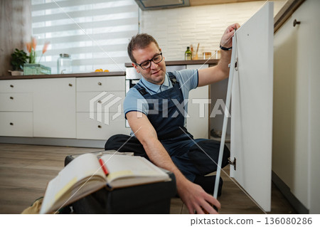 Repairman working on kitchen cabinet door fixing hinges 136080286