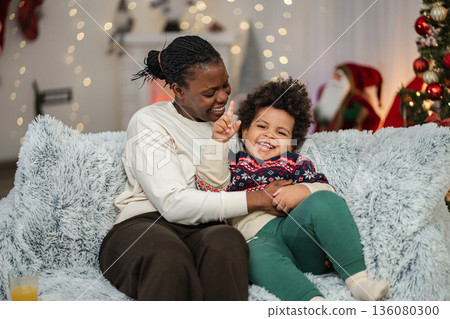Mother and son embracing on couch celebrating Christmas 136080300