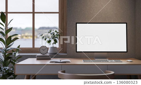 White screen computer with books and clock on wooden table aside window and plant in loft wall room. White screen computer with books and clock on wooden table aside window and plant in loft wall room. 136080323