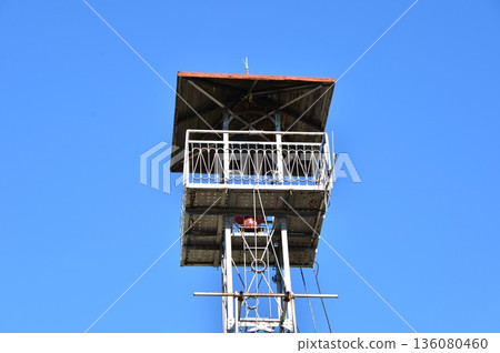 A fire lookout tower towering into the blue sky 136080460