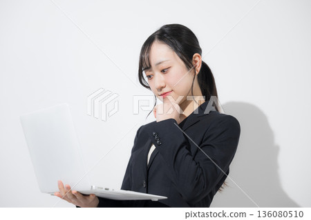 A young woman in a suit holding a laptop. Business image of new graduates and job hunting. Thinking about job hunting recruitment. White background A young woman in a suit holding a laptop. Business image of new graduates and job hunting. Thinking about job hunting recruitment. White background 136080510