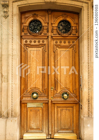Ornate double wooden door on a historic building facade in Paris, France, showcasing classic architecture 136080988