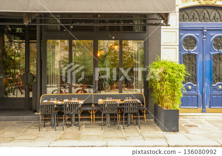 Parisian cafe terrace, quaint outdoor restaurant tables and chairs on sidewalk, charming blue door in old city, travel France 136080992