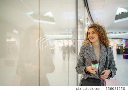 Young adult woman shopping in mall with coffee and bags Young adult woman shopping in mall with coffee and bags 136081258