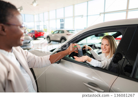 Happy woman buying new car getting keys from saleswoman 136081267