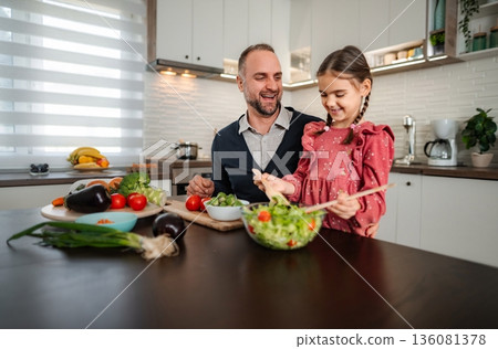Father and daughter preparing healthy salad together in kitchen Father and daughter preparing healthy salad together in kitchen 136081378