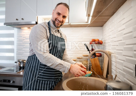 Man washing tomato in kitchen sink preparing food 136081379