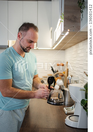 Man preparing morning coffee in a modern kitchen Man preparing morning coffee in a modern kitchen 136081412