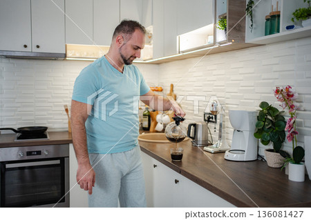 Man pouring fresh hot coffee in kitchen during morning routine 136081427