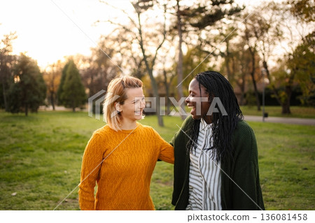 Diverse women friends smiling talking walking in park 136081458