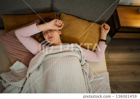 Young woman resting in bed with headache or fever Young woman resting in bed with headache or fever 136081459