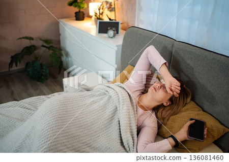 Woman having headache after sleepless night in bedroom 136081460
