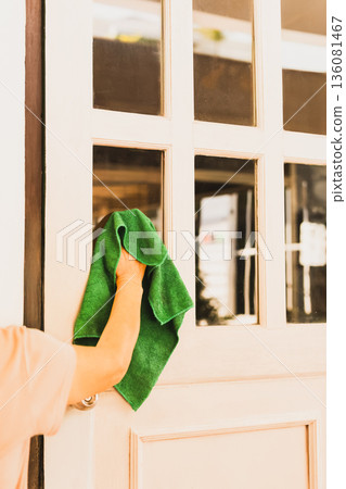 Hosue maid cleaning glass door window at home. 136081467