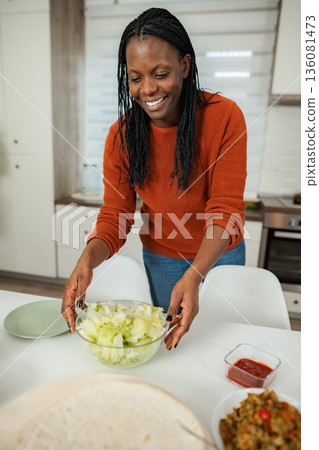 Woman preparing healthy tacos with fresh salad in kitchen Woman preparing healthy tacos with fresh salad in kitchen 136081473