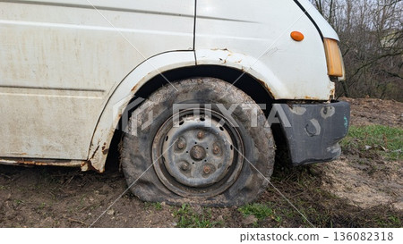 Commercial delivery vehicle halted due to front wheel deflation and mud Commercial delivery vehicle halted due to front wheel deflation and mud 136082318