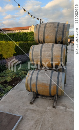 A collection of three elegantly stacked wooden barrels situated beautifully within a garden setting A collection of three elegantly stacked wooden barrels situated beautifully within a garden setting 136082666