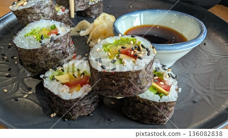 Savor delicious sushi rolls with soy sauce and colorful garnishes for a delightful experience Savor delicious sushi rolls with soy sauce and colorful garnishes for a delightful experience 136082838