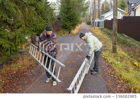 Male workers changing a burnt-out light bulb on light pole and operating at height on roadside utility structure in residential area outdoor scene. 136082905
