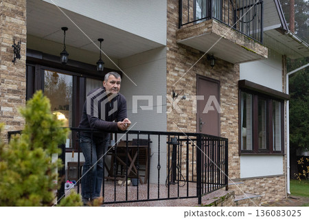 Adult male smoking outdoors near home entrance, quiet pause, natural light, realistic lifestyle scene without emphasis on identity or location. Adult male smoking outdoors near home entrance, quiet pause, natural light, realistic lifestyle scene without emphasis on identity or location. 136083025