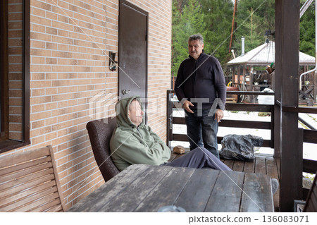 Dialogue aged men in verbal dispute on home porch highlighting tension disagreement communication and relationship issues. 136083071