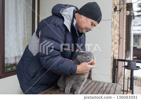 Senior male brushing pet outdoors near house highlighting daily routine compassion and calm interaction with animal. Senior male brushing pet outdoors near house highlighting daily routine compassion and calm interaction with animal. 136083091