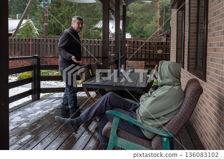 Dialogue aged men in verbal dispute on home porch highlighting tension disagreement communication and relationship issues. Dialogue aged men in verbal dispute on home porch highlighting tension disagreement communication and relationship issues. 136083102