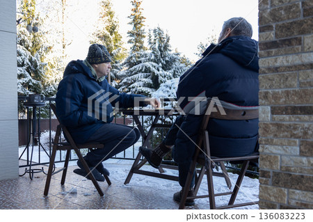 Dialogue aged men in verbal dispute on home porch highlighting tension disagreement communication and relationship issues. 136083223