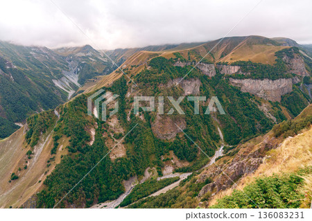 Mountain landscape with green hills and winding river in a valley during cloudy weather Mountain landscape with green hills and winding river in a valley during cloudy weather 136083231