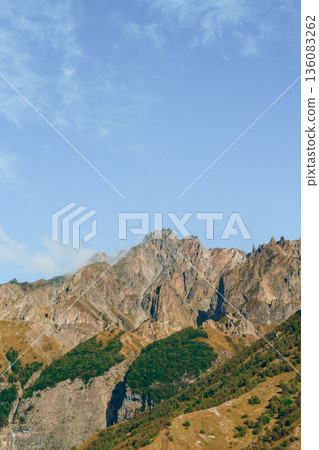 Mountains reach high into the sky with green valleys below on a clear day Mountains reach high into the sky with green valleys below on a clear day 136083262