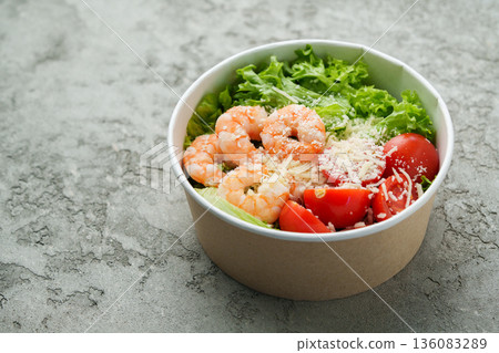 Fresh shrimp salad served in a bowl with lettuce and tomatoes on a gray table Fresh shrimp salad served in a bowl with lettuce and tomatoes on a gray table 136083289