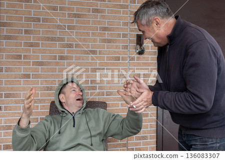 Two adult men arguing on outdoor wooden terrace near house expressing disagreement conflict and strong emotions. 136083307