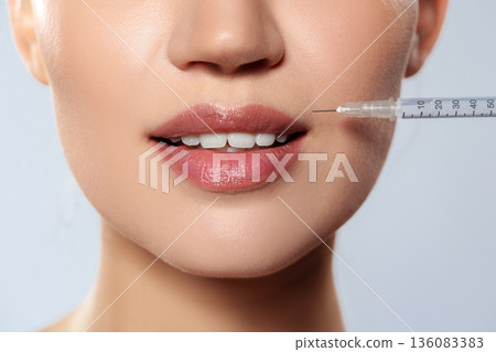 Woman receiving injection for lip enhancement in cosmetic clinic during daytime Woman receiving injection for lip enhancement in cosmetic clinic during daytime 136083383