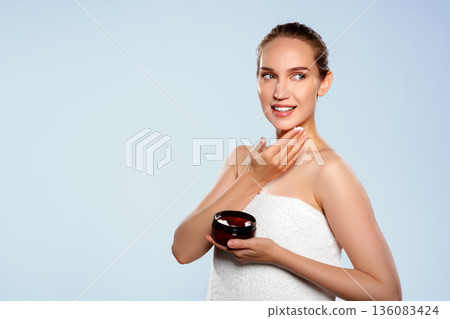 Woman applying skincare product at home during daytime for beauty routine 136083424