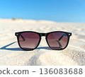 Sunny day. Summer activities. Stylish brown sunglasses on a sandy beach. Close-up. 136083688