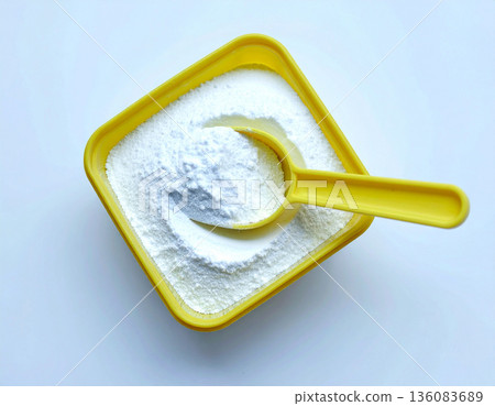 How-to cleaning blogs. Pile of powdered detergent in yellow plastic container with a measuring spoon on a white background. Home washing and cleaning. How-to cleaning blogs. Pile of powdered detergent in yellow plastic container with a measuring spoon on a white background. Home washing and cleaning. 136083689