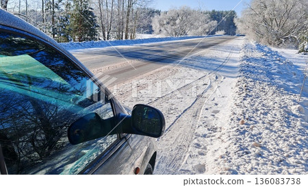 Snowy Winter Road View from Car Side Mirror. Frost-covered trees and snowy road reflected in car mirror during sunny winter countryside drive. Snowy Winter Road View from Car Side Mirror. Frost-covered trees and snowy road reflected in car mirror during sunny winter countryside drive. 136083738
