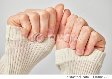 Woman showing her manicured nails wearing a ribbed knit sweater on a neutral background 136084220